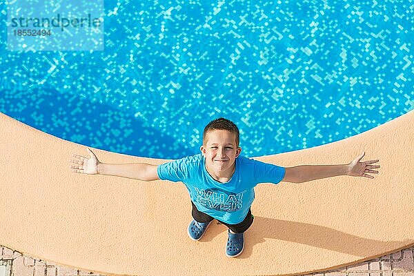Junge steht am Swimmingpool und genießt den Urlaub Ansicht von oben