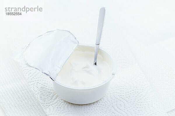 Einfacher griechischer Joghurt in einer Tasse mit Löffel auf weißem Hintergrund