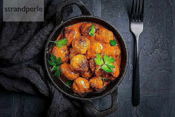 Fleischbällchen mit Tomatensauce in schwarzer Pfanne