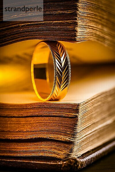 Goldener Ring zwischen den Seiten eines alten Buches im Vintagestil Nahaufnahme  Weichzeichner