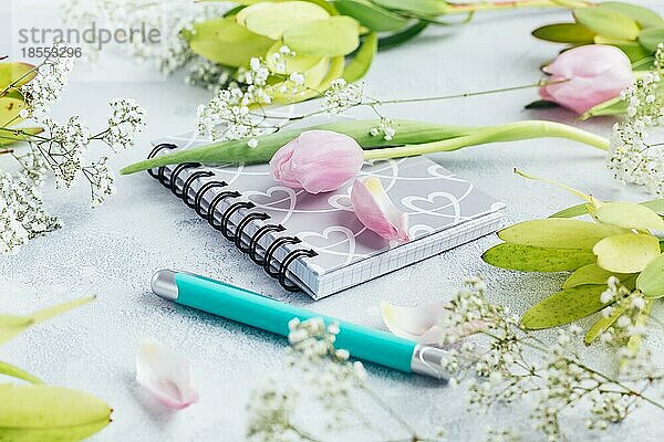 Arbeitsbereich mit Tagebuch  Notizbuch  Stift  Blumen auf hellblauem Hintergrund. Schreibtisch im Heimbüro. Top view femininen Hintergrund. Flachlage  Draufsicht