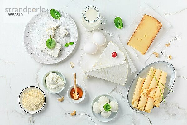 Frische Molkereiprodukte auf weißem Marmor Hintergrund. Sortiment von Käse  Honig  Milch  Joghurt. Ansicht von oben