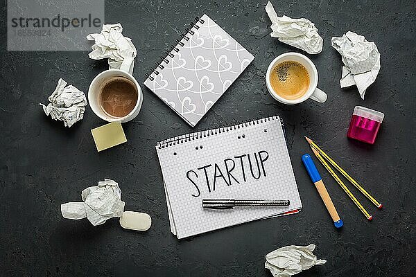 Startup Konzept Notizblock  Kaffee  verworfene Ideen und Schreibgeräte auf schwarzem Schreibtisch