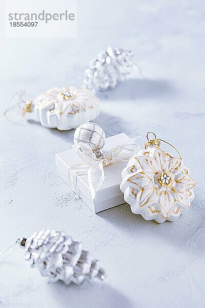 Arrangement aus Weihnachtsschmuck  Kerzen und kleinen Geschenken in schneeweiß