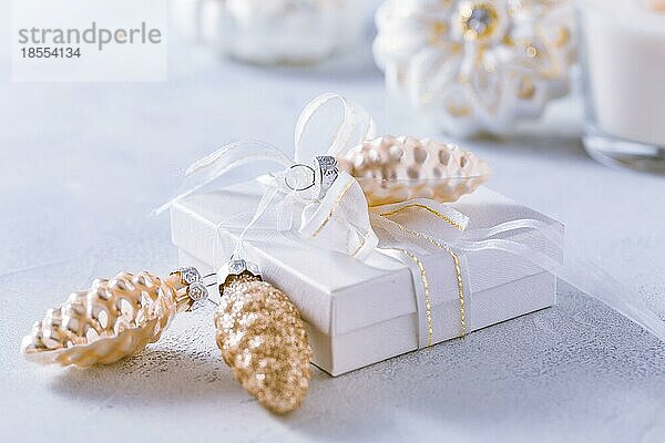 Arrangement von Weihnachtsschmuck  Kerzen und kleinen Geschenken in verschneitem Weiß mit Kopierraum
