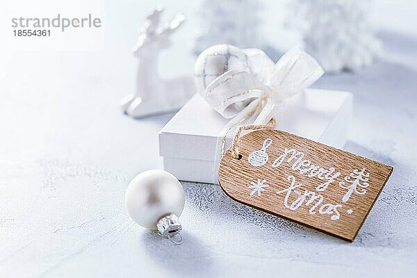 Arrangement von Weihnachtsschmuck  Kerzen und kleinen Geschenken in verschneitem Weiß mit Kopierraum