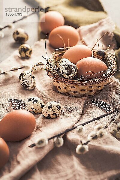 Eier und Wachteleier für Ostern und blühende Trauerweidenzweige auf hölzernem Hintergrund