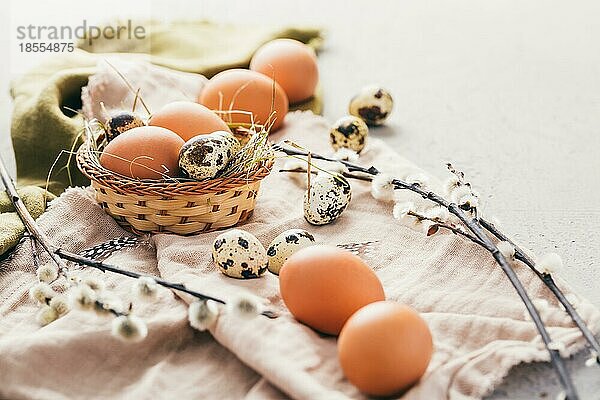 Eier und Wachteleier für Ostern und blühende Trauerweidenzweige auf hölzernem Hintergrund