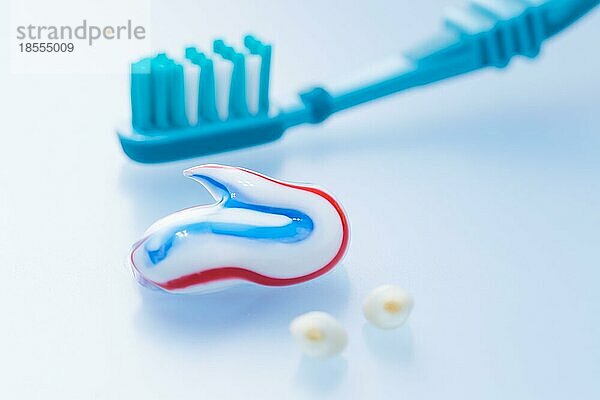 Bunte Zahnpasta und Zahnbürste mit Milchzähnen auf blauem Hintergrund  Konzept der Zahnpflege und Hygiene