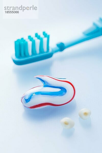Bunte Zahnpasta und Zahnbürste mit Milchzähnen auf blauem Hintergrund  Konzept der Zahnpflege und Hygiene