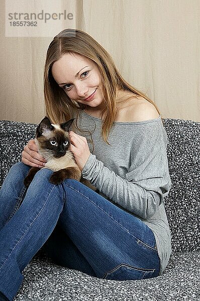Glückliche junge Frau mit siamesischer Katze