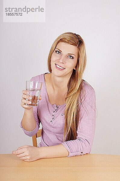 Junge Frau hält ein Glas Wasser