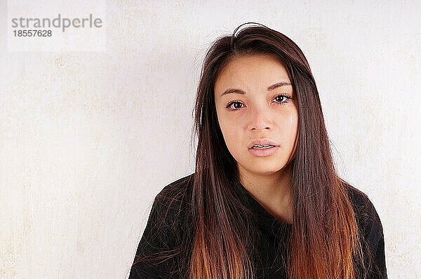 Weinende junge asiatische Frau  der die Tränen über die Wangen laufen