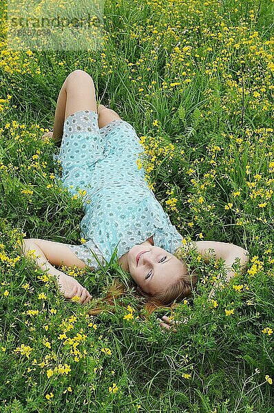 Glückliche junge Frau  die sich in einem Blumenfeld entspannt