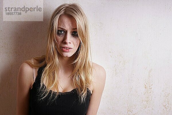 Weinerliche  traurige junge Frau mit verschmiertem Make-up  die weint und unglücklich aussieht
