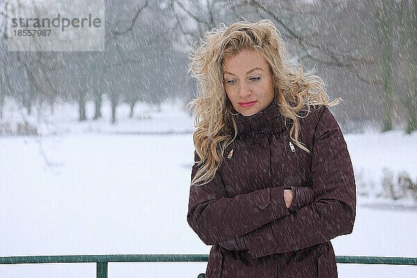 Frierende Frau bei starkem Schneefall leidet unter Winterdepression