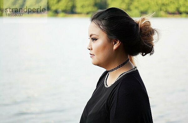 Profil oder Seitenansicht einer jungen asiatischen Frau  die am Seeufer steht