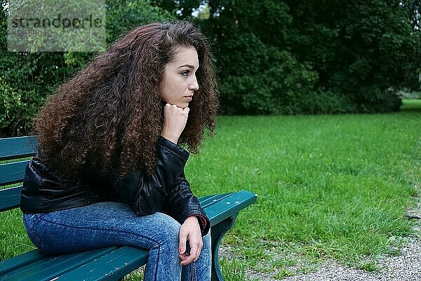 Trauriger weiblicher Teenager auf einer Parkbank sitzend