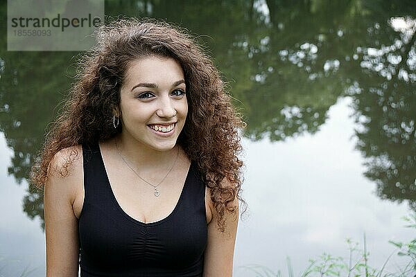 Schöne junge spanische Frau entspannt an einem Teich