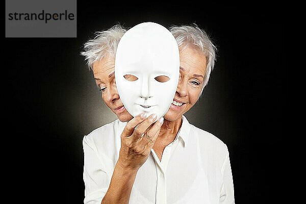 Ältere Frau versteckt glückliches und trauriges Gesicht hinter einer Maske  Konzept für manische Depression oder bipolare oder dramatische Komödie Drama
