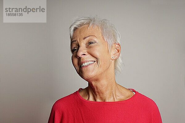 Glückliche ältere Frau mit trendigen kurzen weißen Haaren lachend. grauer Hintergrund mit Kopierraum