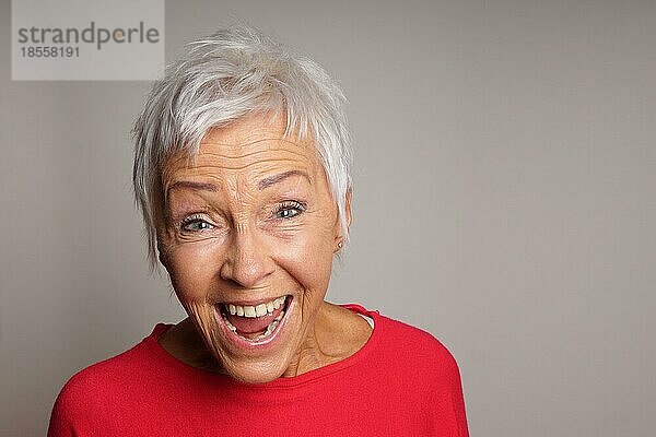 Glückliche reife ältere Frau mit kurzen weißen Haaren lachend