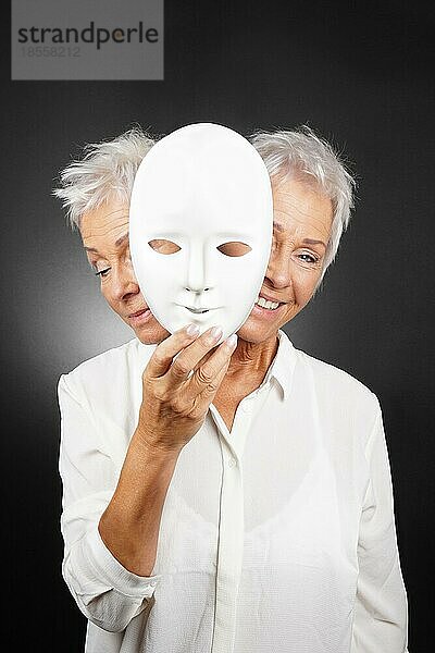 Ältere Frau versteckt glückliches und trauriges Gesicht hinter einer Maske  Konzept für manische Depression oder bipolare oder dramatische Komödie Drama