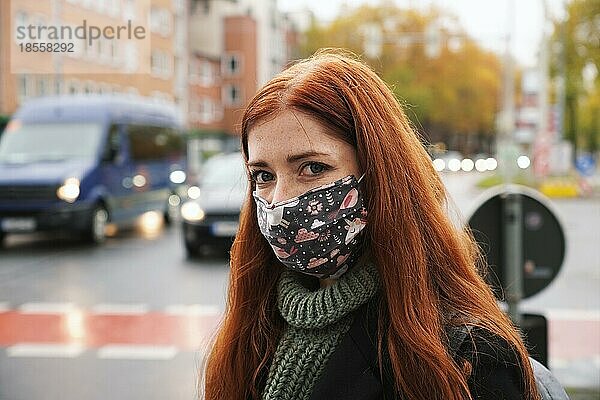 Junge Frau mit Gesichtsmaske im Freien als Fußgängerin im Stadtverkehr  neue normale Covid-19-Coronavirus-Pandemie und Luftverschmutzung Konzept  echte Menschen Lebensstil im Winter