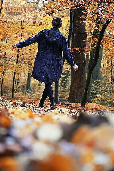 Rückansicht einer Frau  die einen Herbstspaziergang im Wald genießt - offener Lebensstil im Freien in der Herbstzeit - mit Kopierraum