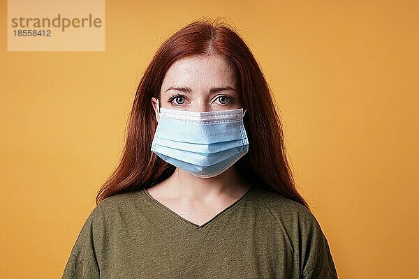 Studioporträt einer jungen Frau  die eine medizinische Gesichtsmaske trägt  die Mund und Nase bedeckt - Schutz vor dem Coronavirus