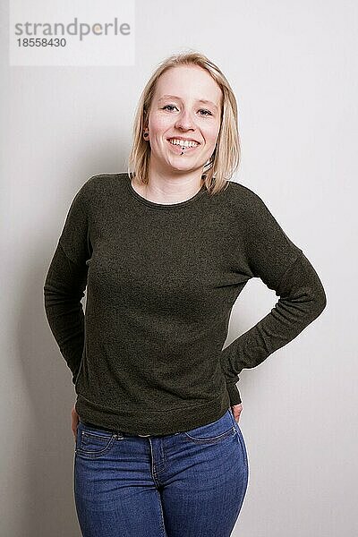 Junge blonde Millennial-Frau lächelnd  drei Viertel Länge echte Menschen Porträt