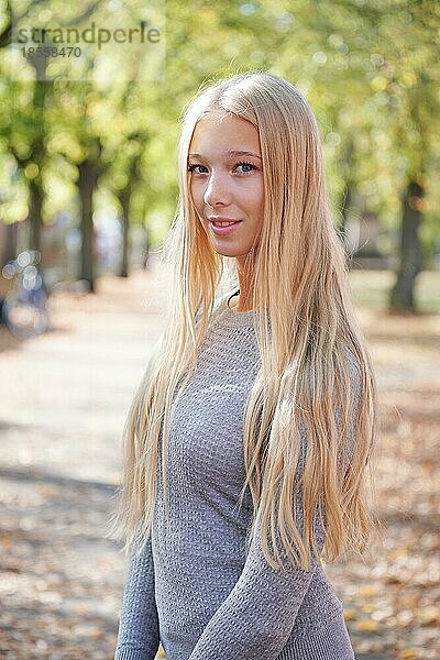 Porträt eines Teenagers mit langen blonden Haaren  der einen sonnigen Tag im Freien genießt