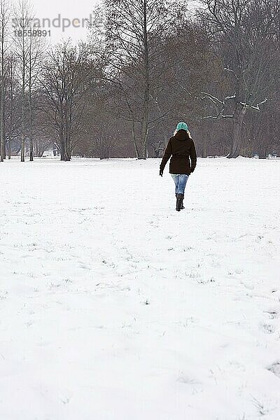Rückansicht einer Frau  die im Winter über ein verschneites Feld läuft. mit Kopiervorlage