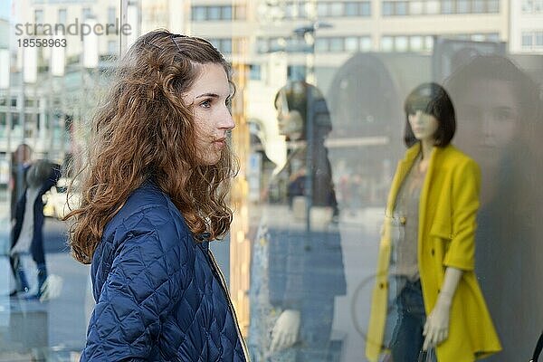 Junge Frau betrachtet die Modeauslage im Schaufenster