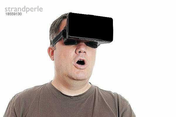 Mann mittleren Alters  der ein Virtual-Reality-Headset trägt  ist von der VR-Erfahrung überwältigt