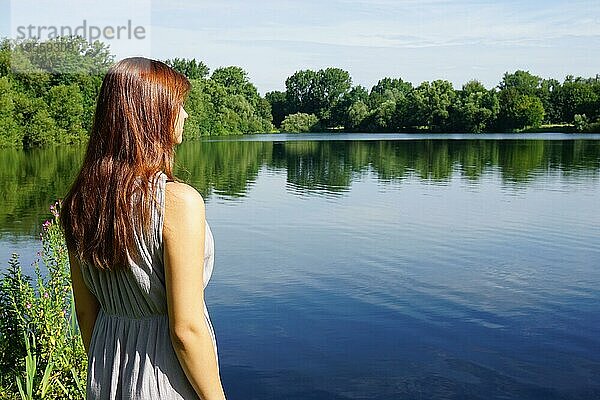 Rückansicht einer jungen Frau mit Blick auf einen idyllischen See mit Kopierraum