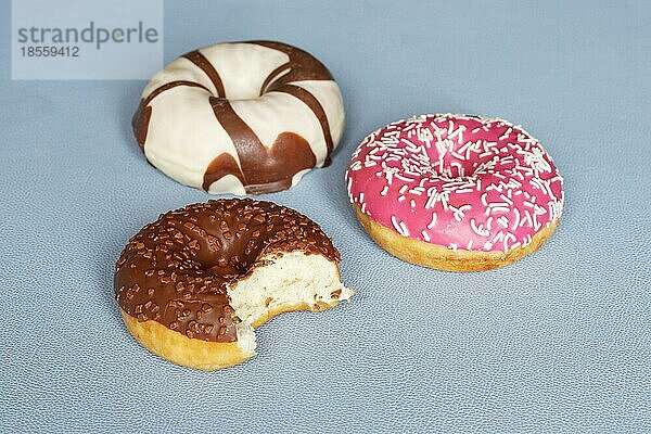 Donuts oder Krapfen mit unterschiedlichem Zuckerguss. Schokoladendonut  dem ein Biss fehlt