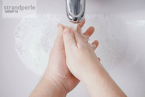 Händewaschen mit Wasser und Seife aus der persönlichen Perspektive - Hygienekonzept mit unkenntlicher männlicher Person und geringer Tiefenschärfe