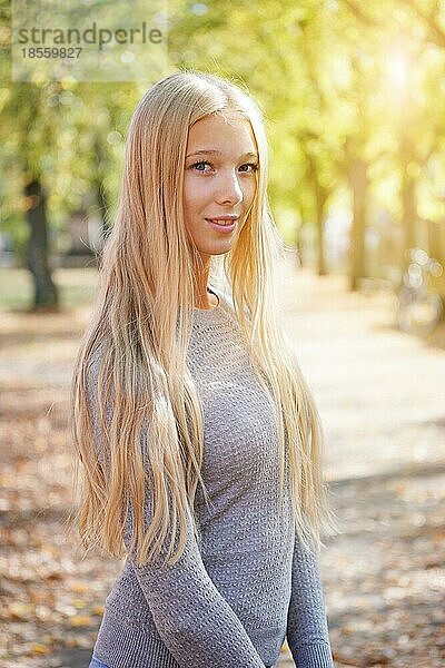 Porträt einer blonden jungen Frau im Freien  die den sonnigen Tag genießt - mit Sonnenreflexionsfilter