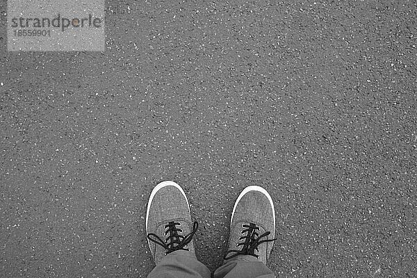 Füße in Segeltuchschuhen auf der Straße stehend - Fuß-Selfie aus persönlicher Perspektive Standpunkt - Asphalt Hintergrund mit Kopie Raum