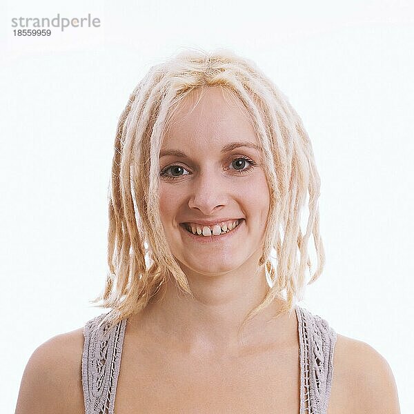 Fröhlich lächelnde junge Frau mit blonden Dreadlocks und Zahnlücke - Studio-Kopffoto vor weißem Hintergrund