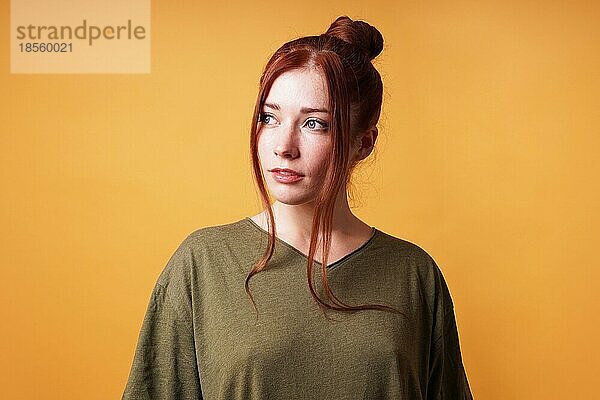 Studioporträt einer hübschen jungen Frau mit rotem Haarknoten  die wegschaut