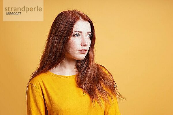 Junge Frau mit ausdruckslosem Gesicht  die über einen Gedanken nachdenkt - gelber Hintergrund mit Leerzeichen