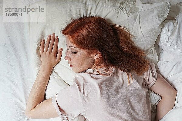 Junge Frau im Bett schlafend auf dem Bauch mit dem Kopf auf dem Kissen