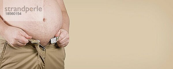 Unkenntlicher übergewichtiger korpulenter Mann mit dickem Bauch  der nicht in seine Hose paßt - Adipositas und Adipositas-Konzept in breitem Webbanner-Format mit Kopierraum