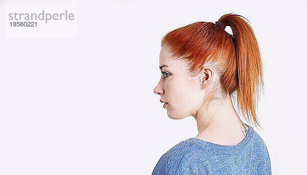 Seitenprofil einer jungen Frau mit gefärbten roten Haaren  die mit einem Haargummi zu einem Pferdeschwanz zurückgebunden sind
