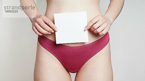 Mittelteil einer nicht erkennbaren Frau in Unterhose  die ein leeres Schild mit Text über dem Bauch als Konzept für Frauengesundheit oder gynäkologische Erkrankungen hält