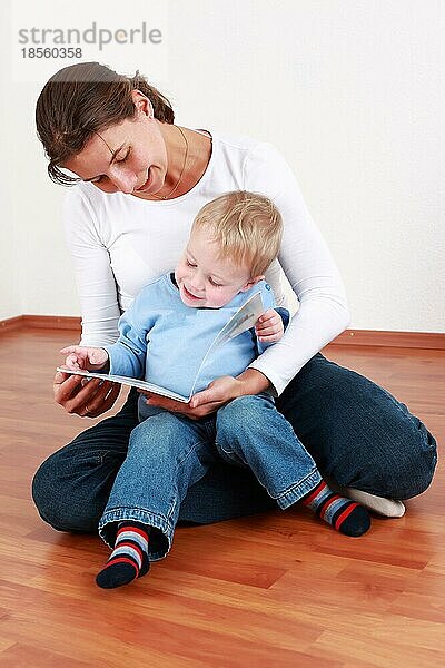 Kluger kleiner Junge liest mit Mama oder Kindergärtnerin