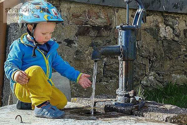 mit Wasser spielnder Junge Wasserpumpe