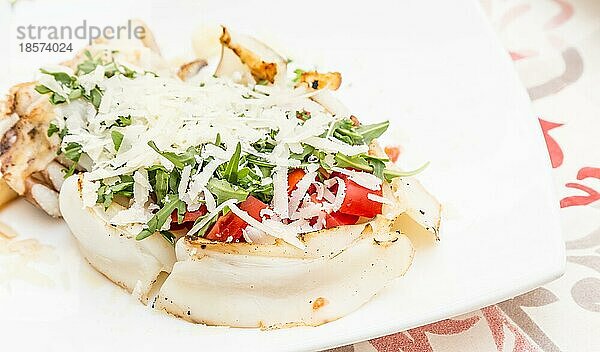 Italienisches Restaurant in Gallipoli  Region Apulien (Süditalien) . Traditioneller Tintenfisch mit frischem Salat  Tomaten und echtem Parmigiano Käse. Tageslicht